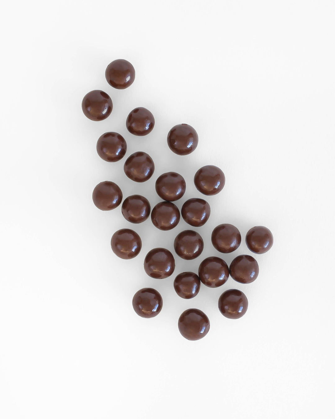 Chocolate-covered caramels scattered on a white background