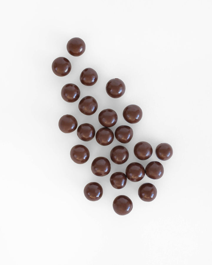 Chocolate-covered caramels scattered on a white background