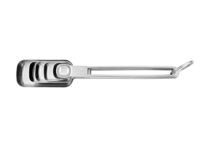 Different sizes of stainless steel measuring spoons stacked inside each other. 