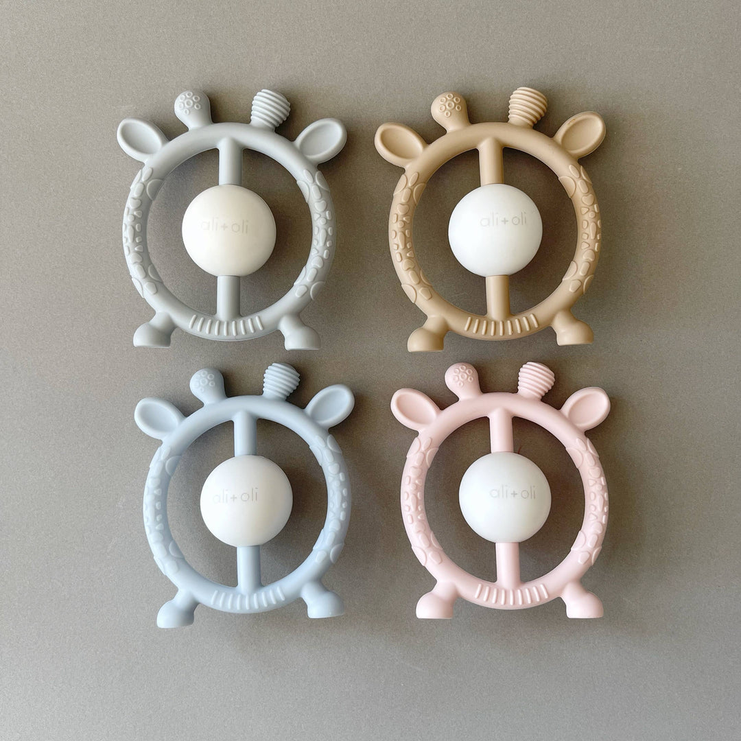 Four baby teething toys with steering wheel design on a beige background