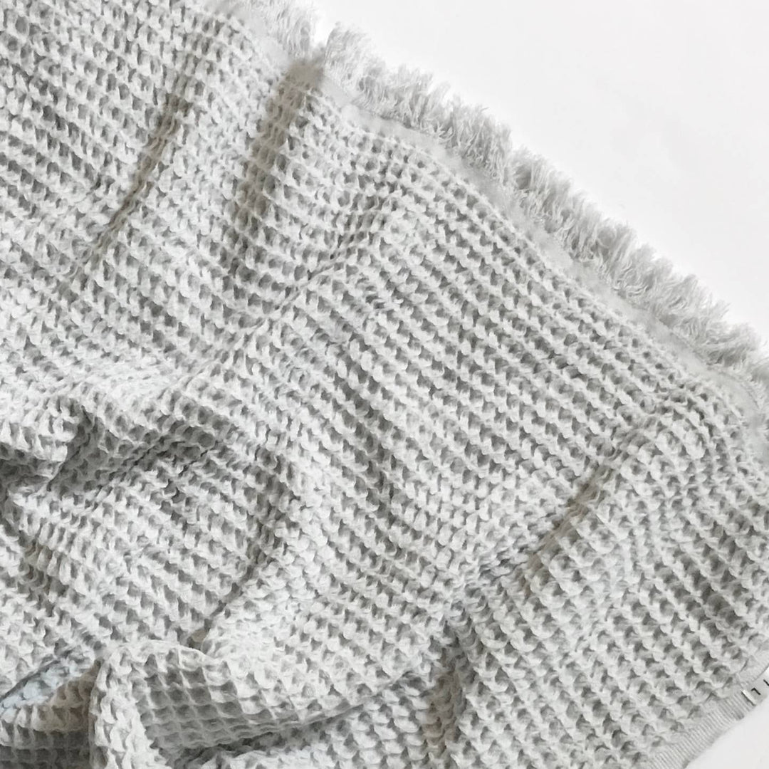 Textured gray blanket with fringe on a light background