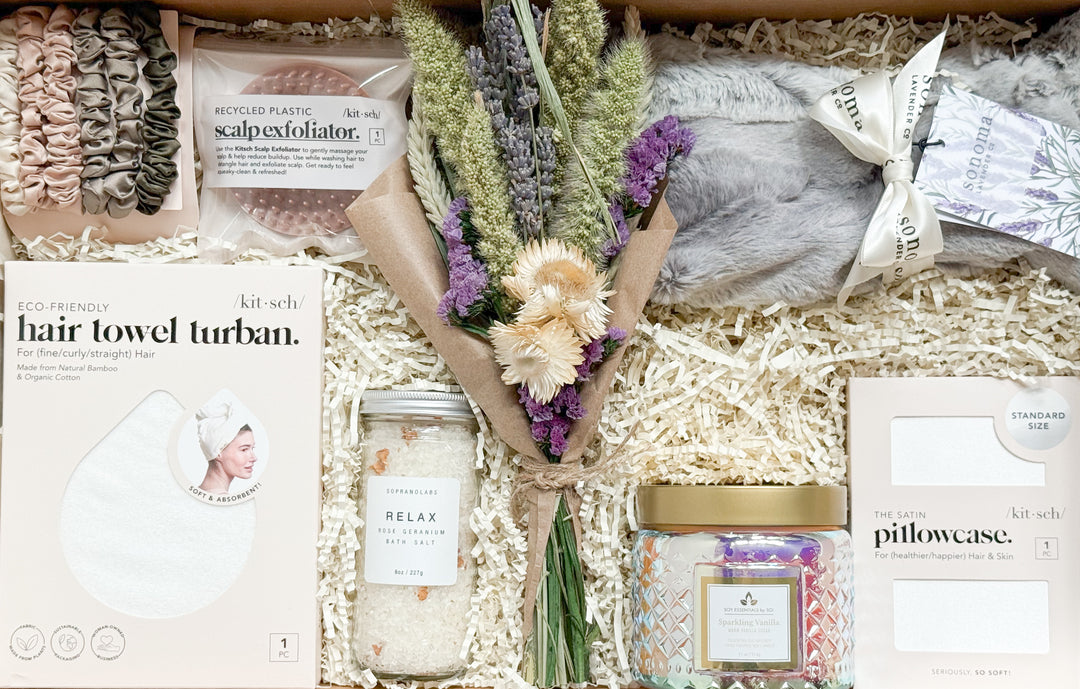 Gifting box with bath products, flowers, and packaging on a white background