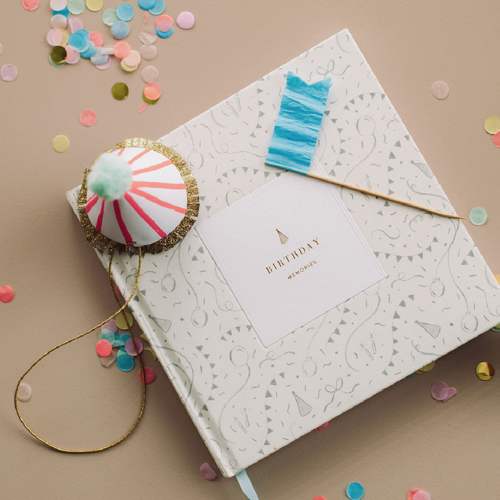 Decorative birthday card with a small cake-shaped gift and confetti on a beige background