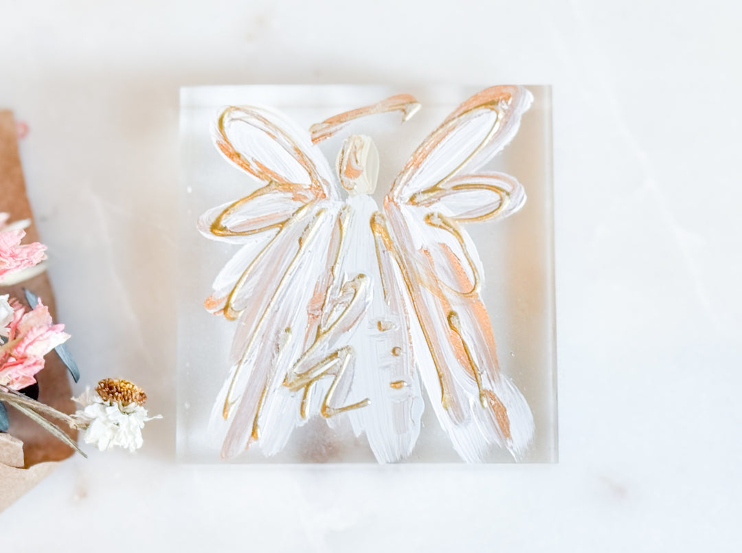 Decorative angel wall art with gold accents on a white background