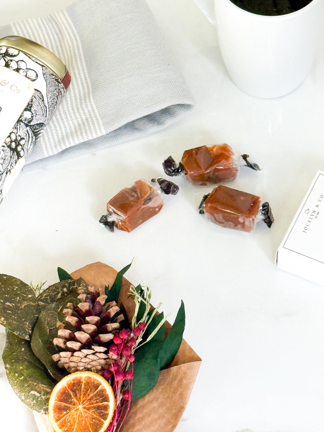 Candies on a white surface with a decorative arrangement of leaves and an orange slice.