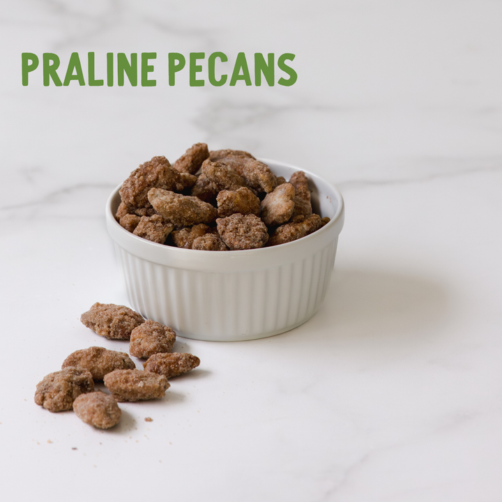 Praline pecans in a white bowl on a light background with &