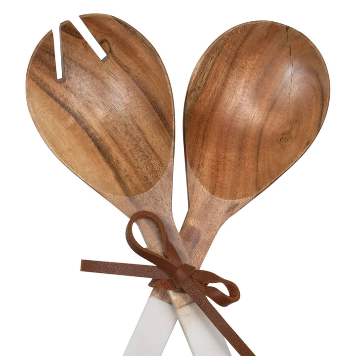 Wooden salad servers with a brown ribbon on a white background