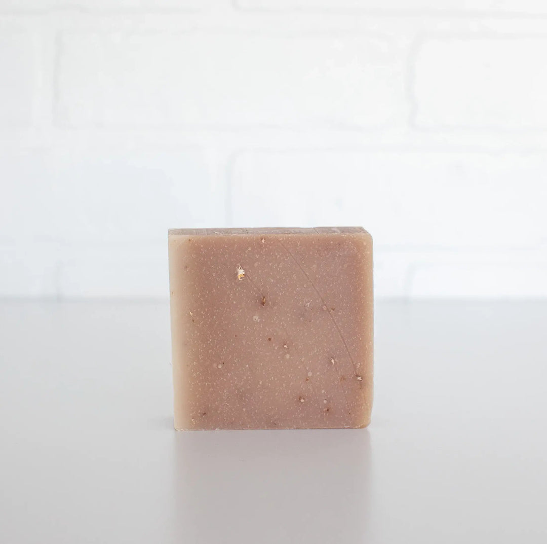 Square bar of soap with visible specks on a white background