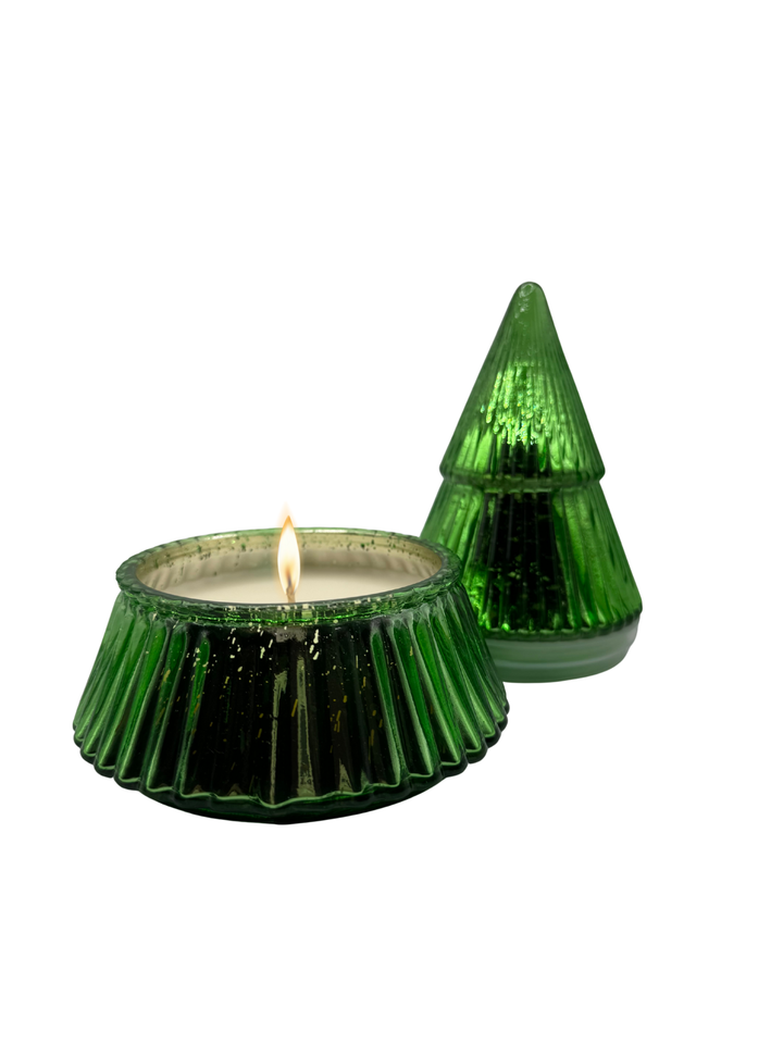 Opened green glass Christmas tree-shaped candle lit on a white background