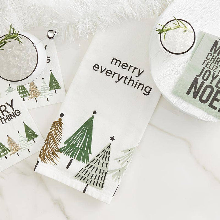 Christmas-themed napkins and a kitchen towel with trees and text on a white surface