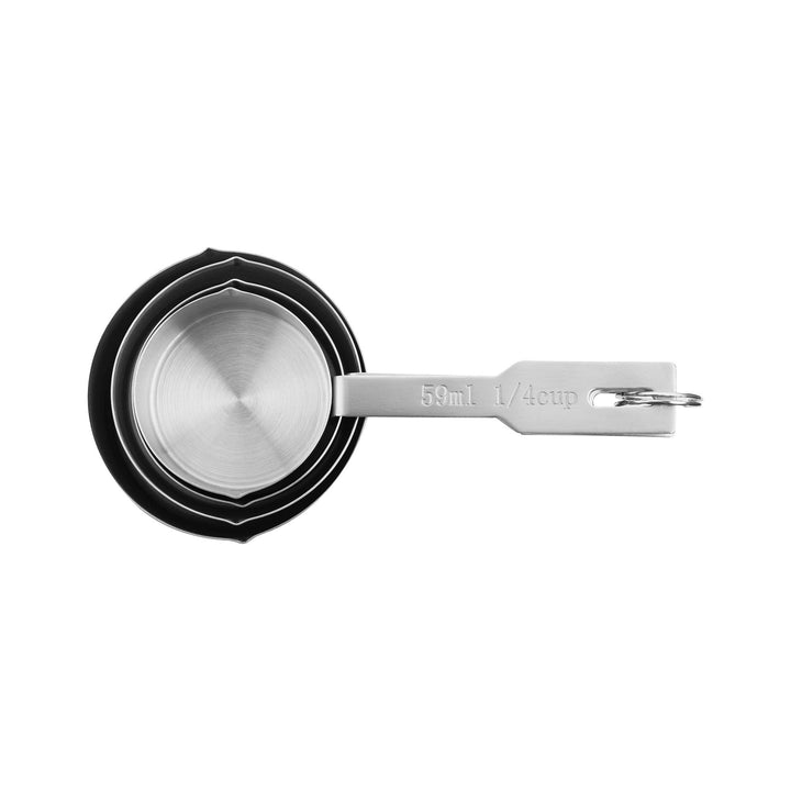 4 stainless steel measuring cups stacked in each other on a white surface. 