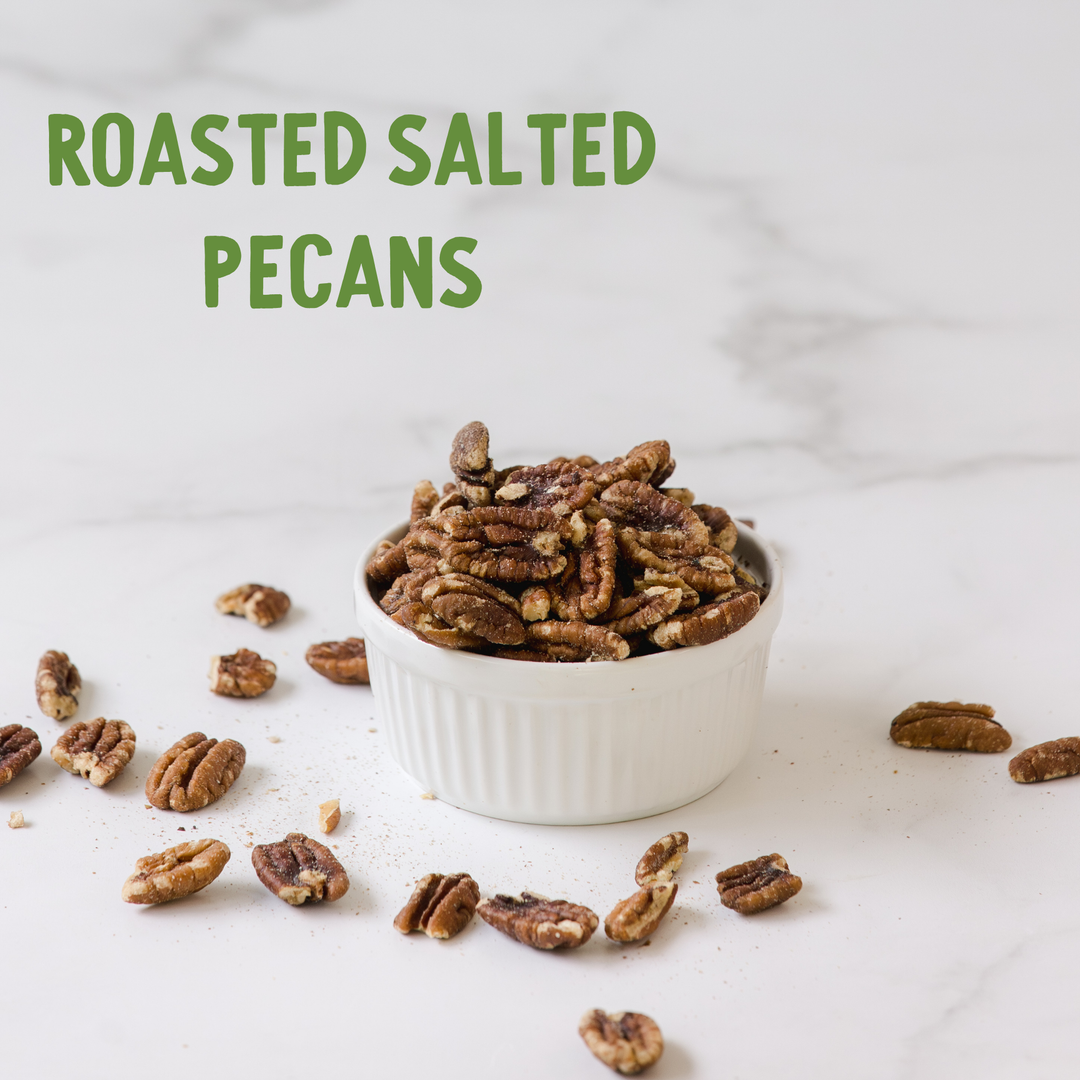 Roasted salted pecans in a white bowl with scattered pecans on a light background
