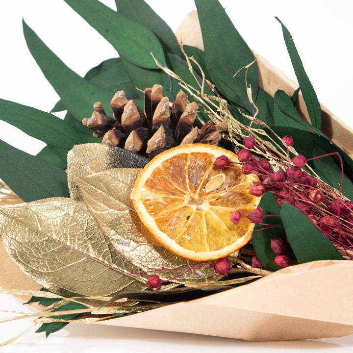 Decorative arrangement with dried orange, pine cones, and leaves on a white background