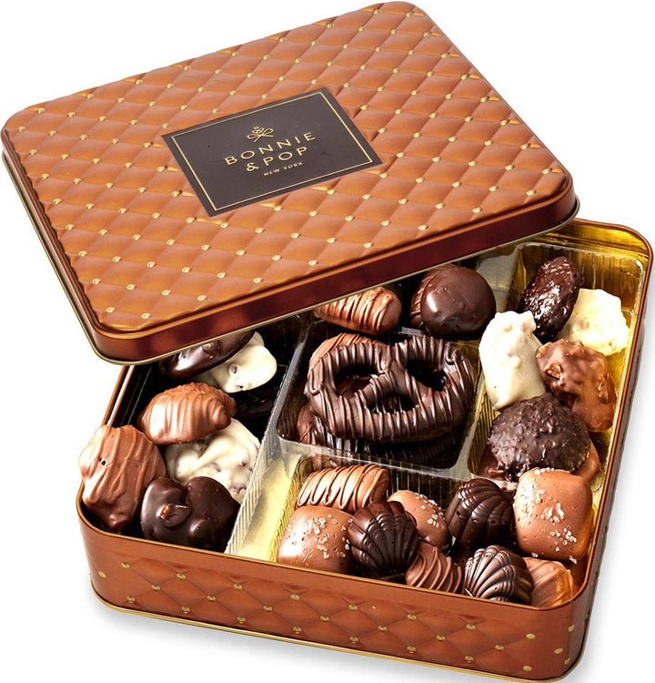 Open brown quilted chocolate tin filled with assorted chocolates on a white background