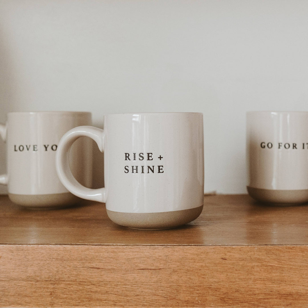 Mugs with motivational phrases on a wooden surface.
