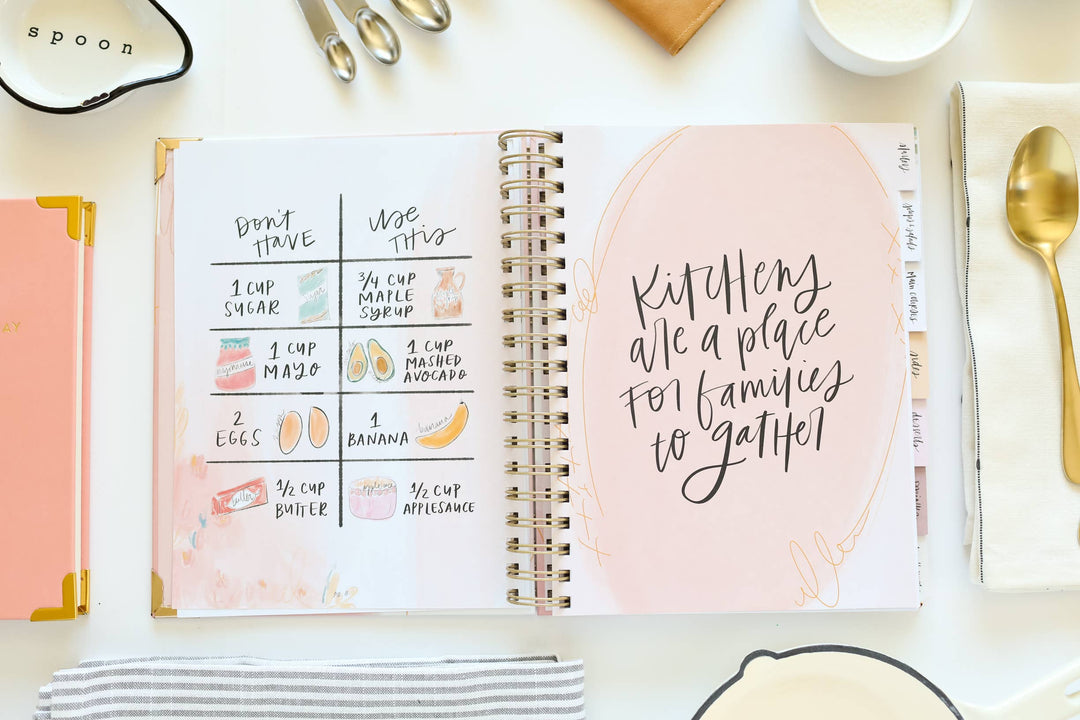 Cookbook open to an ingredient replacement page with kitchen utensils and decor around it