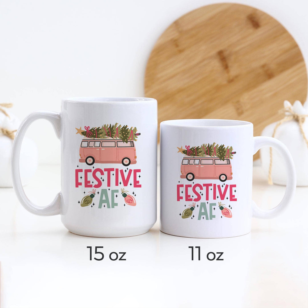 Two white mugs with festive designs and text of two different sizes next to each other on a white background