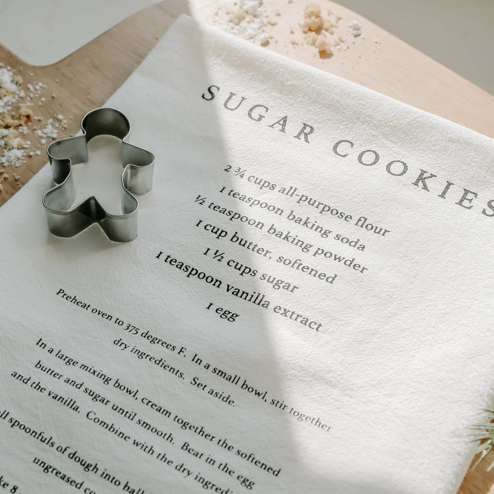 Sugar cookies recipe on a towel and a gingerbread man cookie cutter