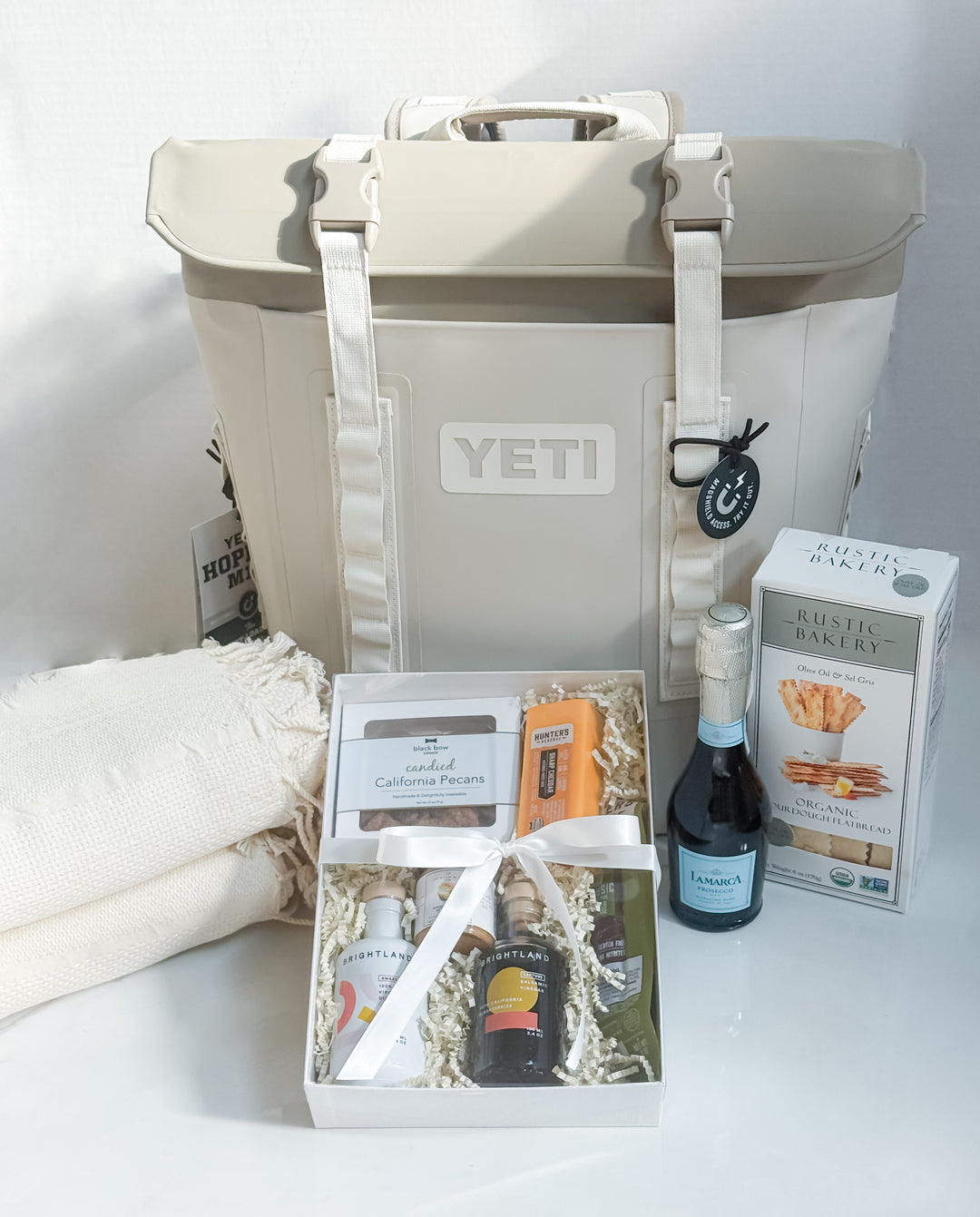 YETI cooler with a snack set, bottle of wine and a blanket on a white background