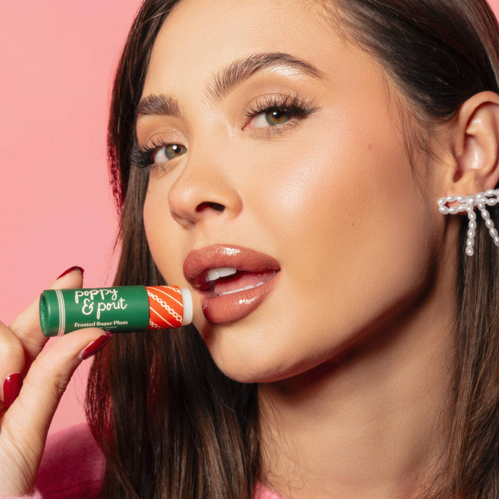 Woman holding a lip balm with a pink background