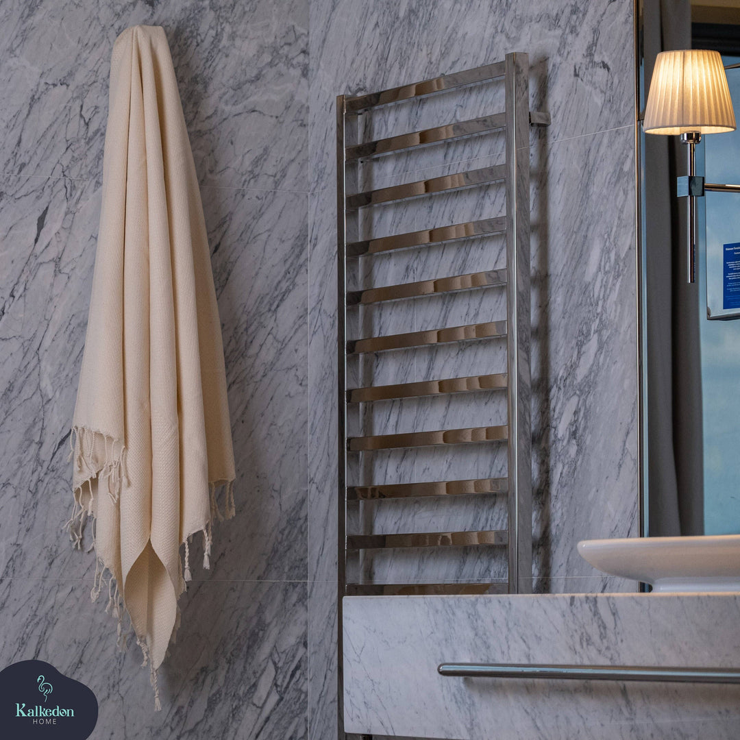 Bathroom setting with a towel hanging on a marble wall, wooden towel rack, and light fixture.