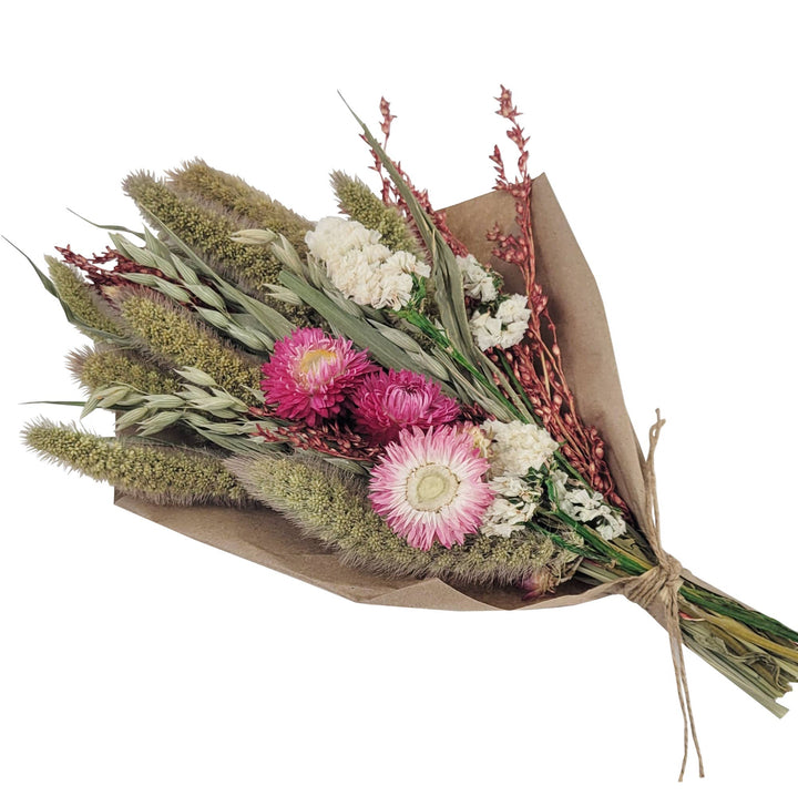A petite bouquet with pink strawflowers, statice flowers, avena, and sorghum, wrapped in brown paper.