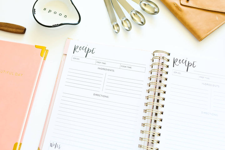 Recipe book with a pen and other items on a white surface