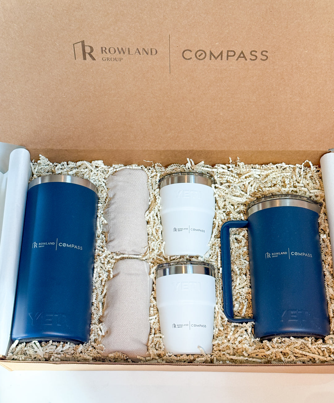 Set of tumblers and cloths in a gift box with Rowland Group and Compass branding.