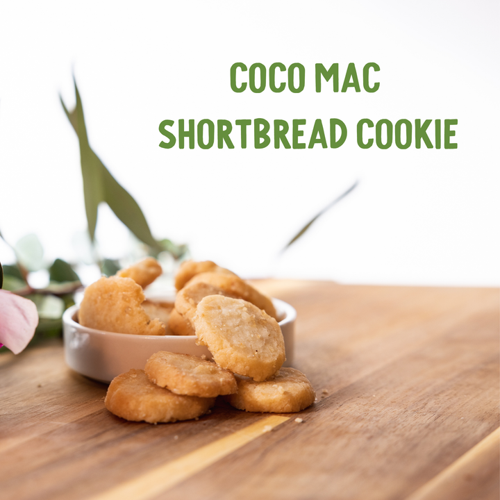 Coco Mac shortbread cookies on a wooden surface with a blurred background