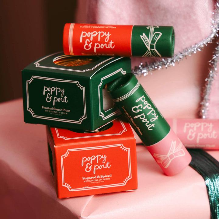 Poppy &amp; Pout lip care packaging on a pink surface