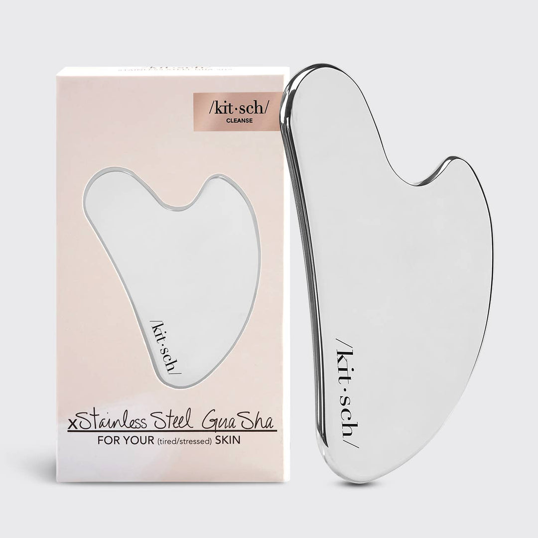 A stainless steel Gua Sha tool next to its packaging, labeled Kitsch.