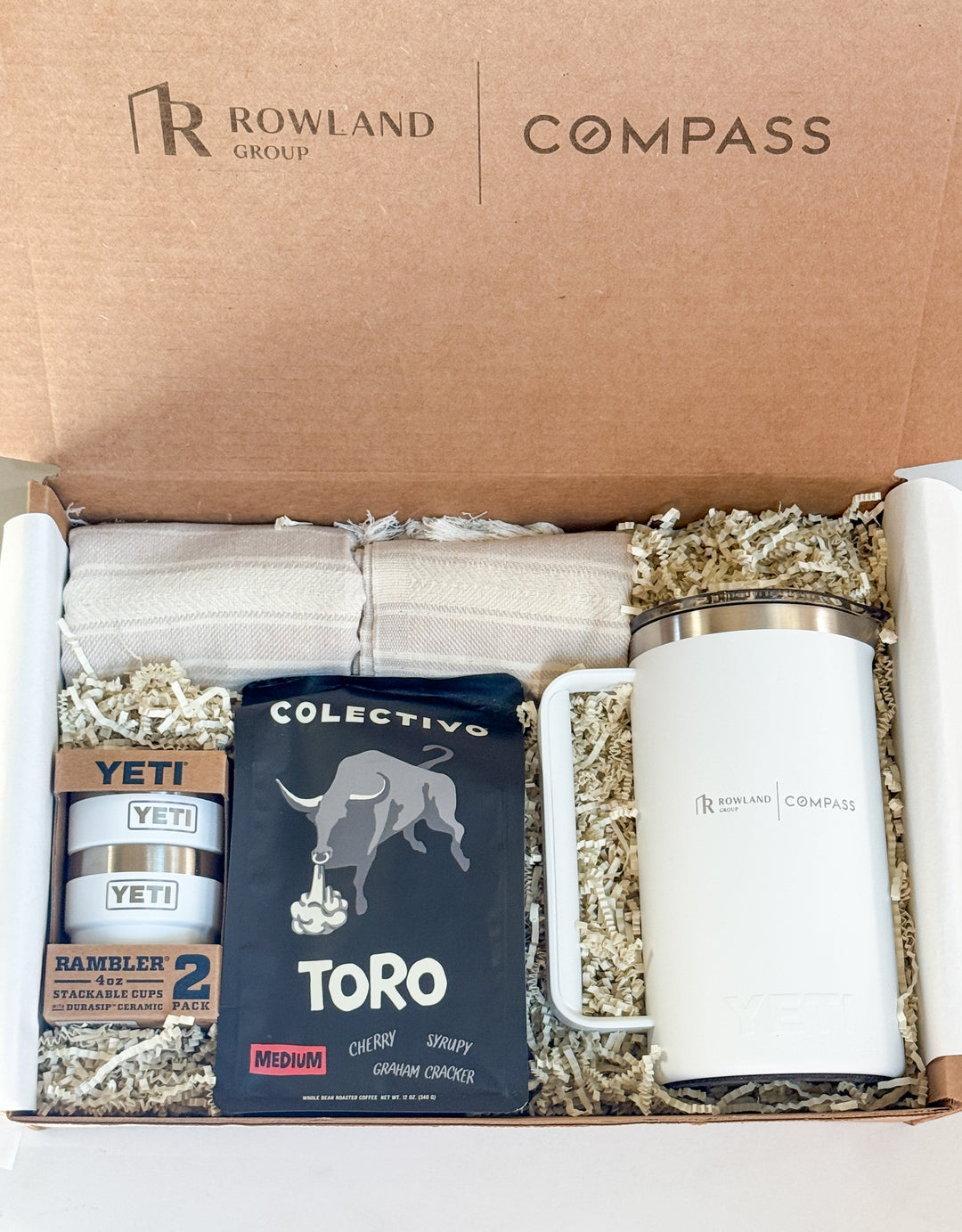 Gift box with Colectivo Toro coffee, YETI tumblers, a blanket and a Rowland Group branded French press.