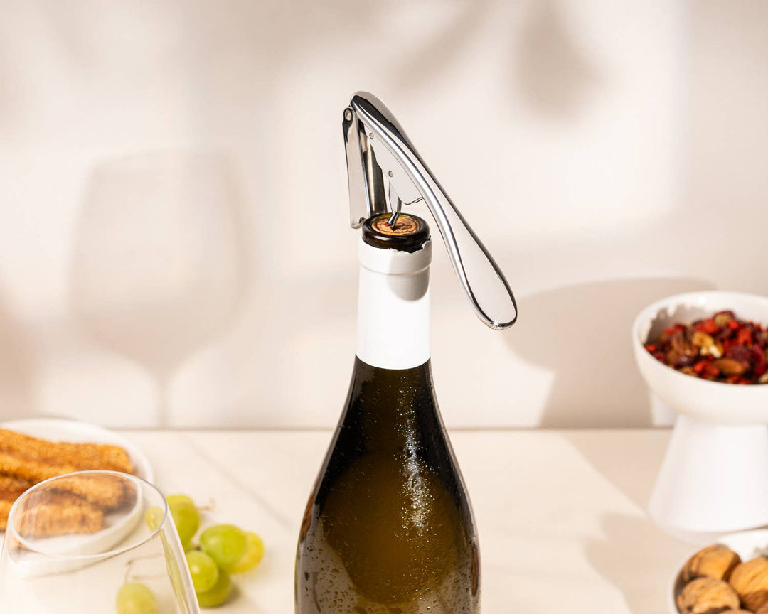 Bottle of wine with a corkscrew on a table with snacks