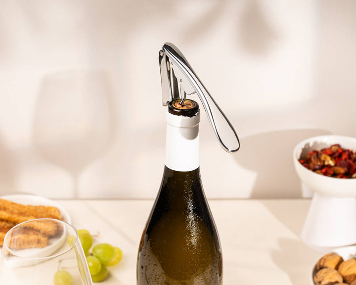 Bottle of wine with a corkscrew on a table with snacks