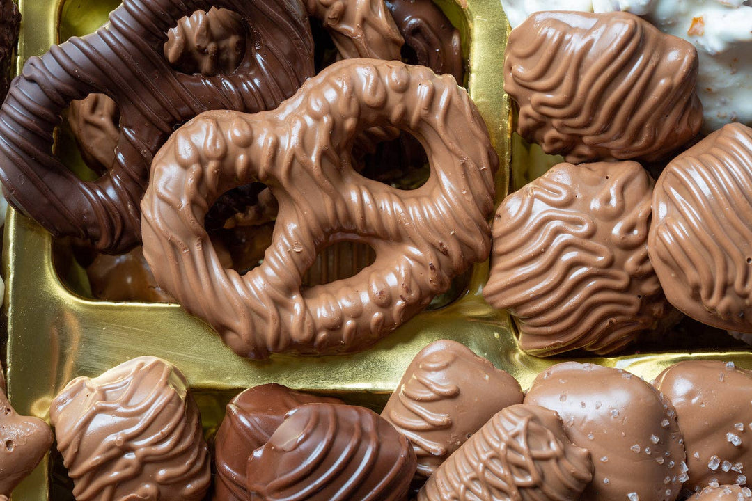 Assorted chocolate candies including pretzels and nuts in a box.