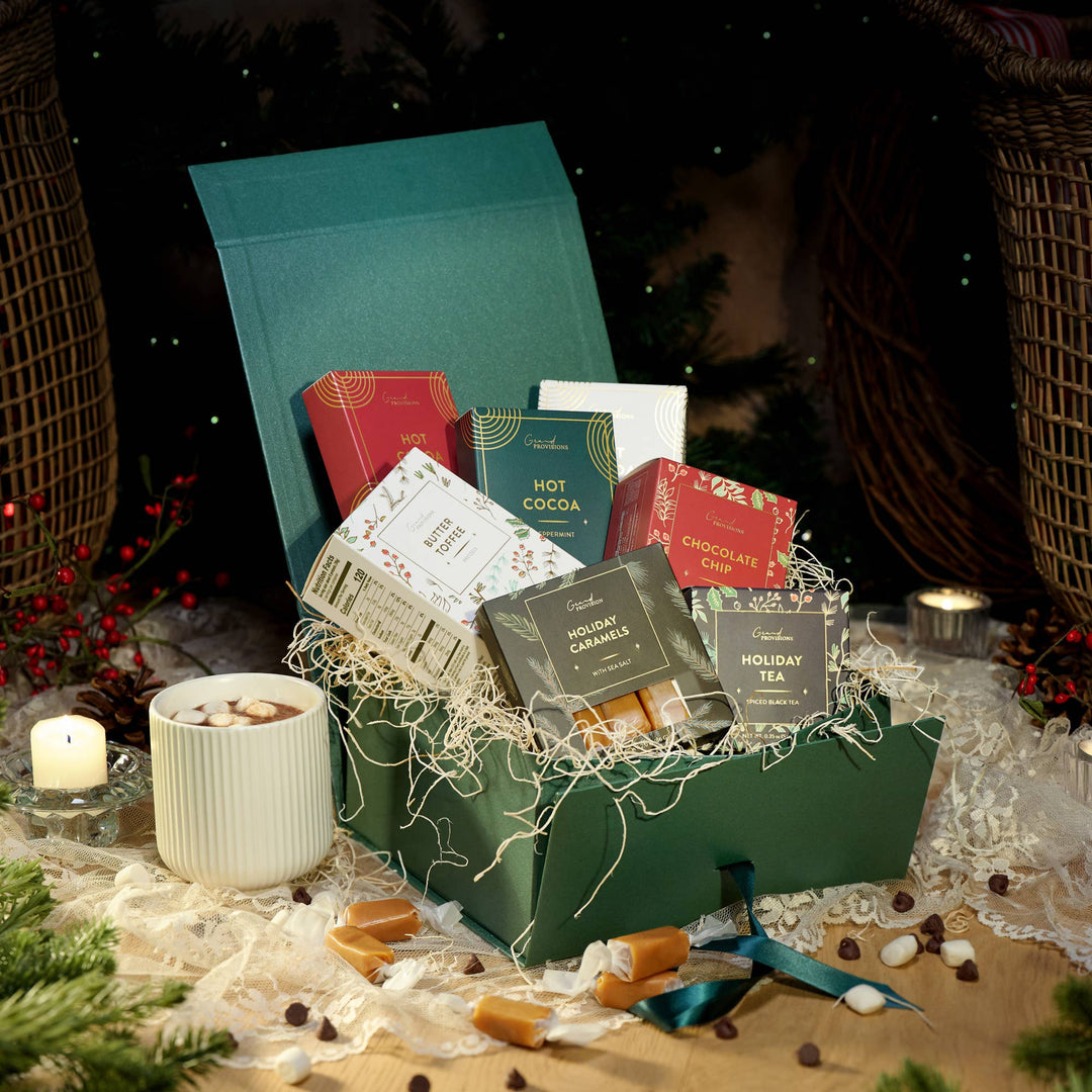 Gift basket with various holiday treats packaged in a cozy setting with candles and decorative items.