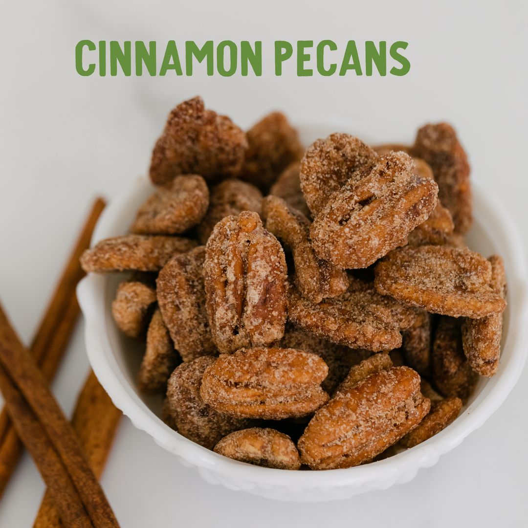 Cinnamon pecans in a white bowl with cinnamon sticks on a light background