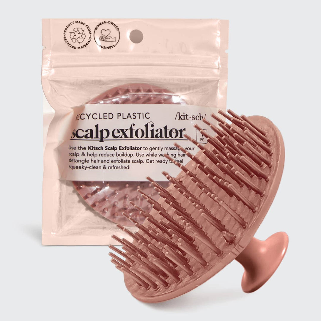 A terracotta-colored scalp exfoliator with flexible bristles, packaged in a clear plastic bag with product information.