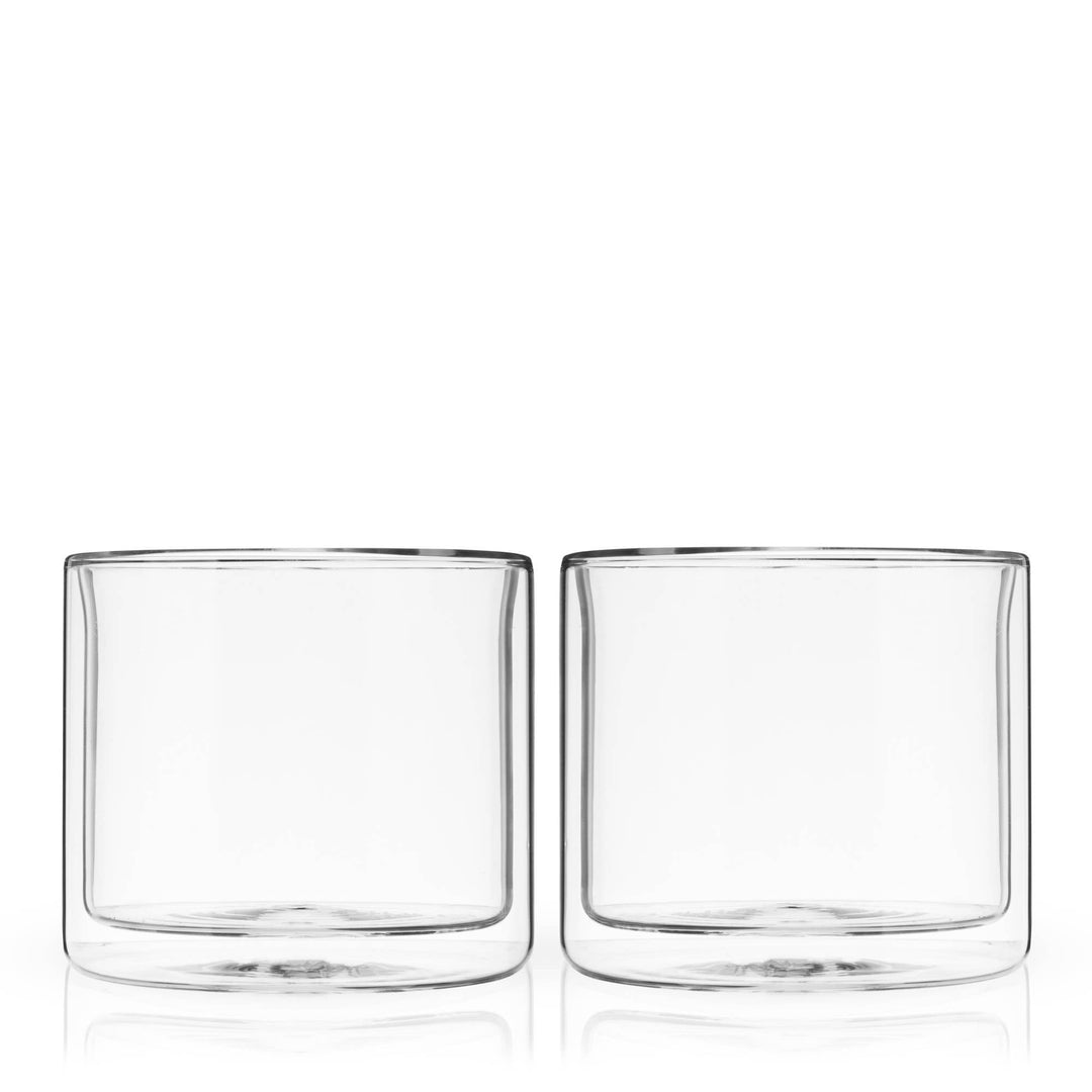 Two clear whiskey glasses on a white background