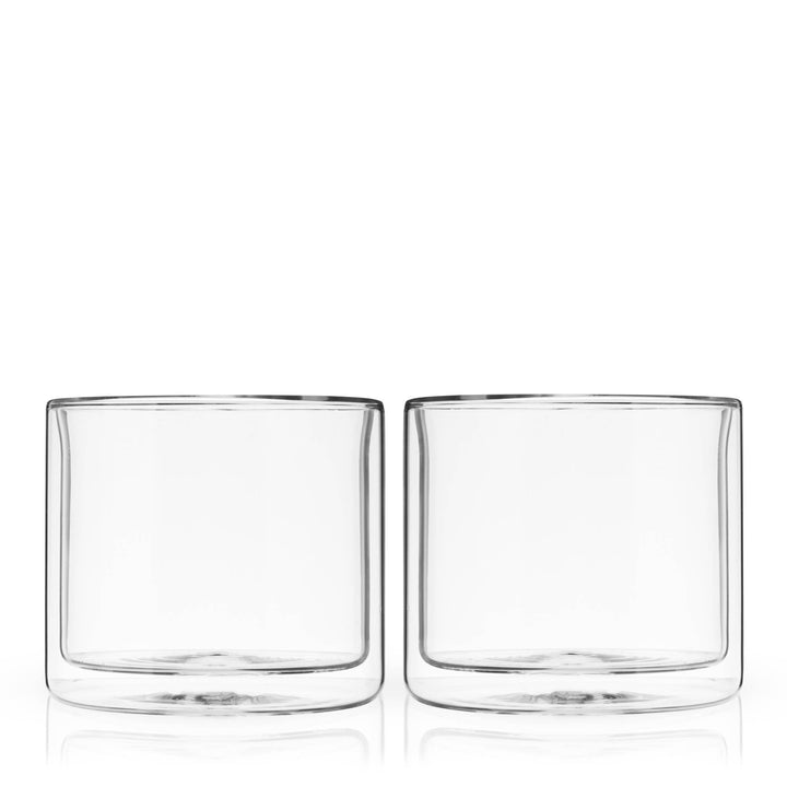 Two clear whiskey glasses on a white background