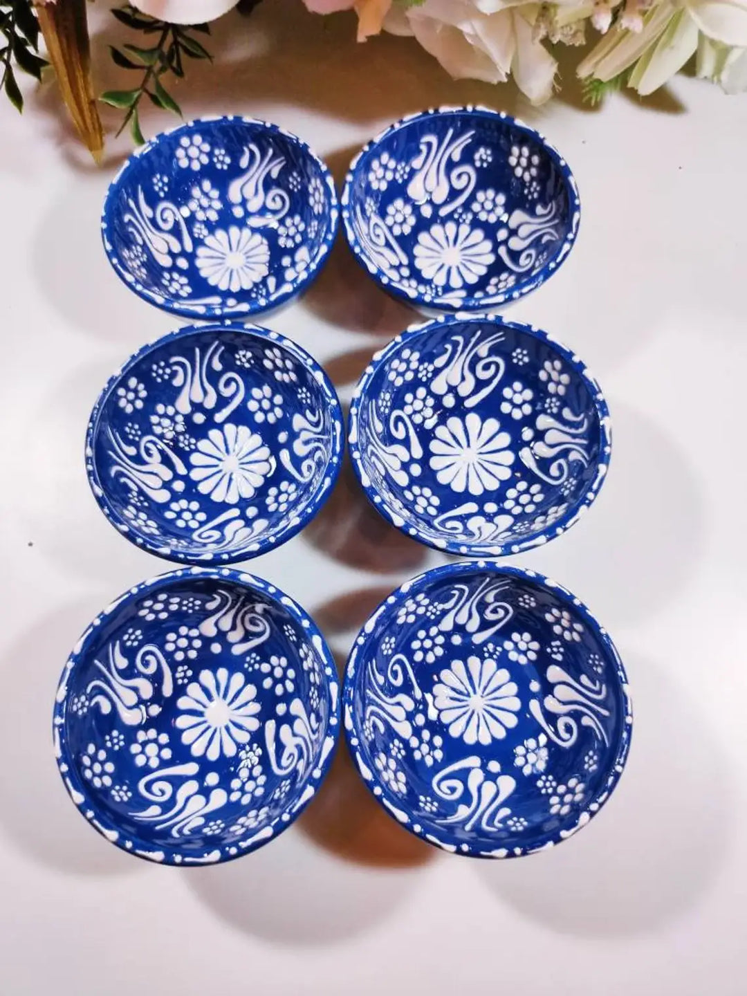 Set of six blue ceramic bowls with white floral patterns on a white background.