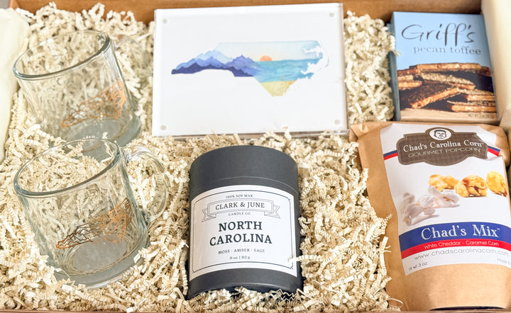 Gift box with two glass mugs, a candle labeled &