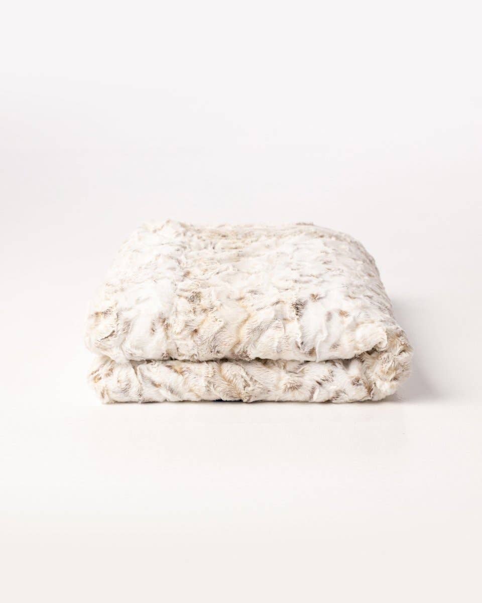 Folded soft, furry blanket on a light gray background