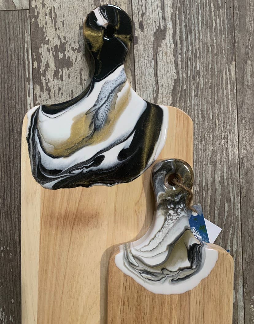 Decorative cutting boards with black, white, and brown abstract patterns on a wooden board against a wooden background.