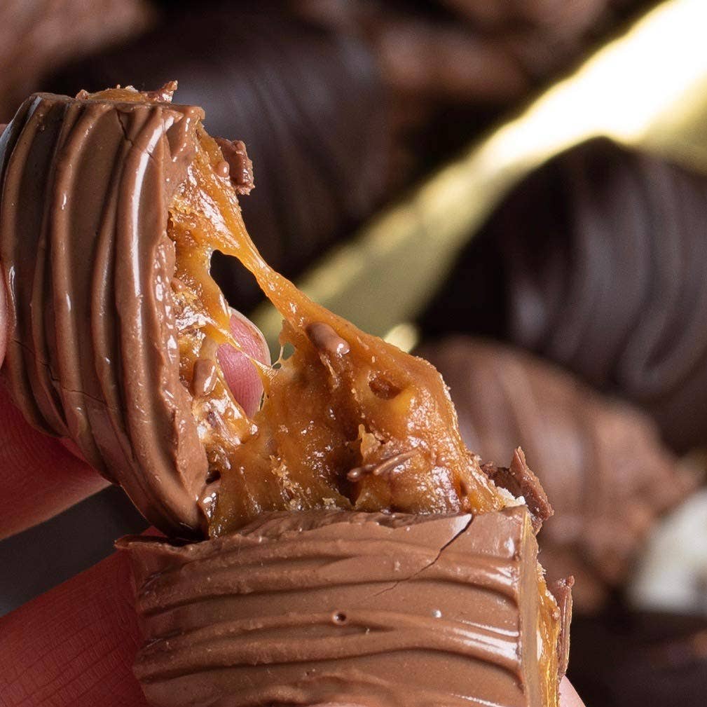 Close-up of a chocolate candy being pulled apart, revealing a gooey filling.