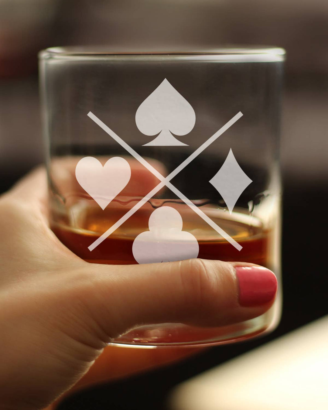 Glass with playing card suits held by a hand, blurred background