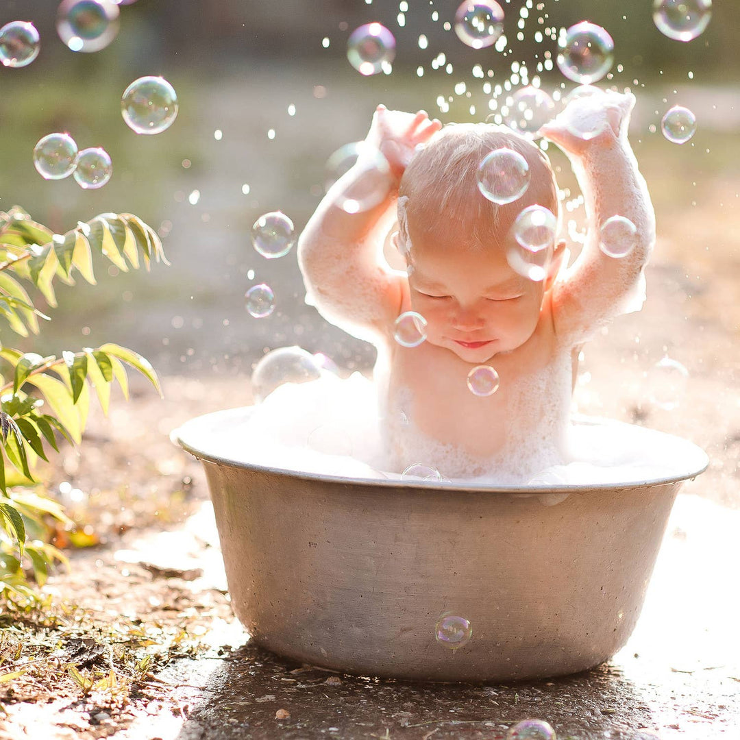 Baby playing with bubbles outdoors in a basin