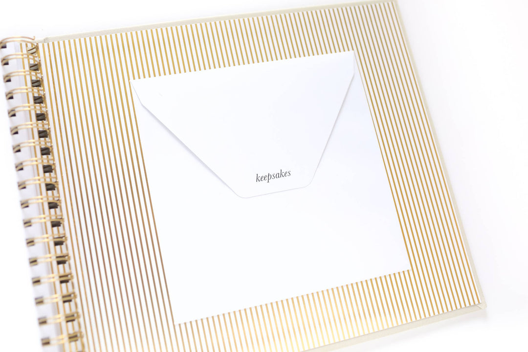 Notebook with gold spiral binding and a white card on a white background