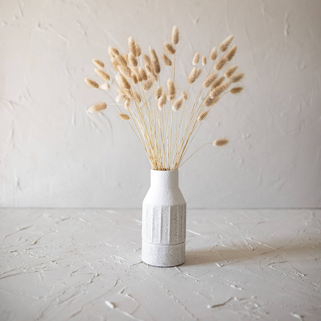White textured vase with dried bunny tails against a light gray background