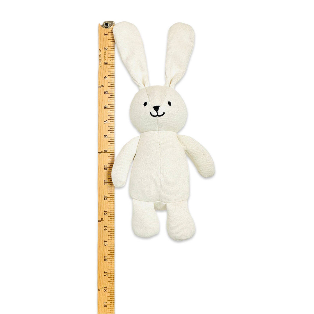 White plush bunny toy next to a ruler on a white background